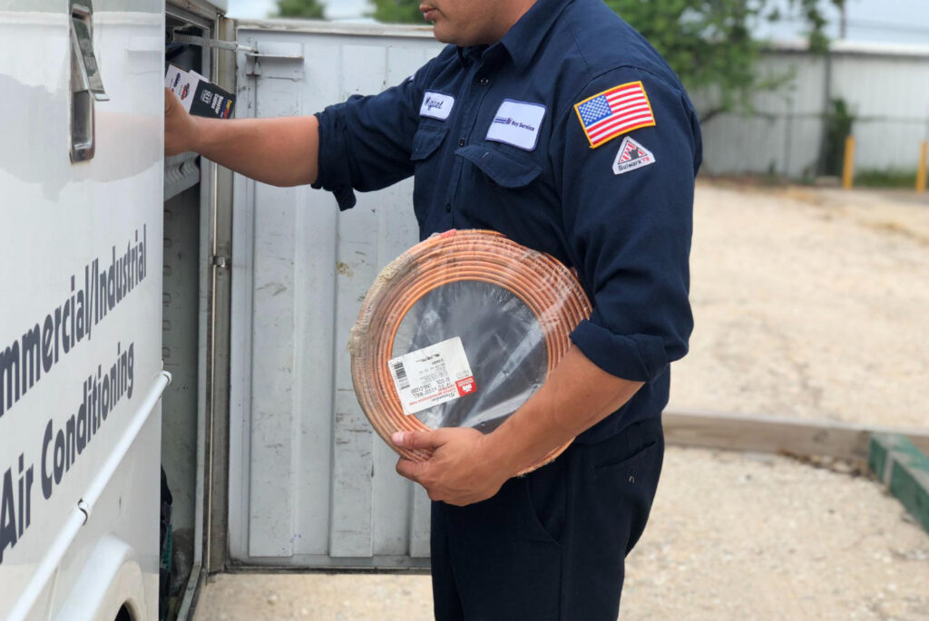 HVAC technician loading copper tubing for commercial refrigeration system installation